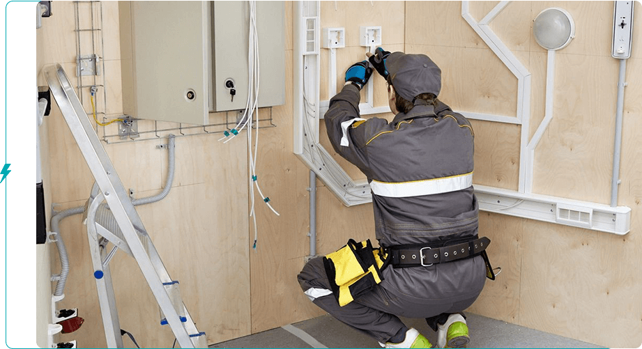 A man in grey work suit working on electrical box.