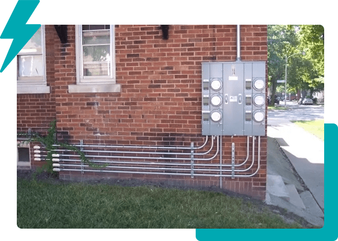 A brick building with electrical boxes and wires.